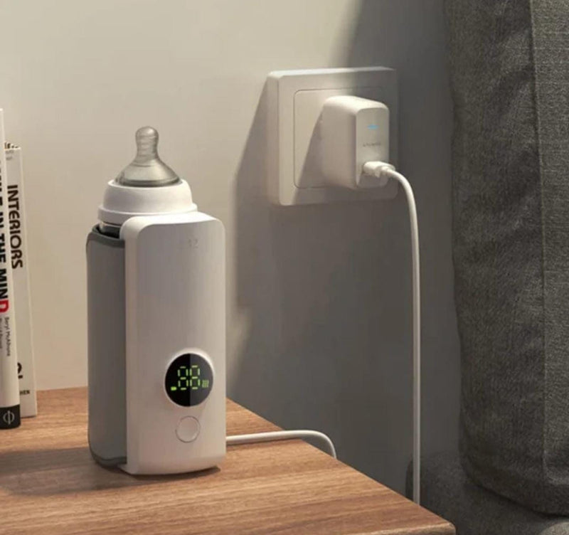 calentador de biberones recargable usb blanco con pantalla digital y biberon en mesa junto a enchufe