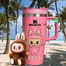 Termo Stanley Labubu edición limitada en color rosa con diseño de personaje divertido en un ambiente de playa